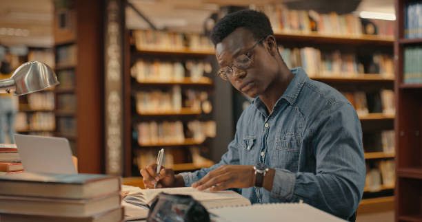 Serious young black male student in a library studying 